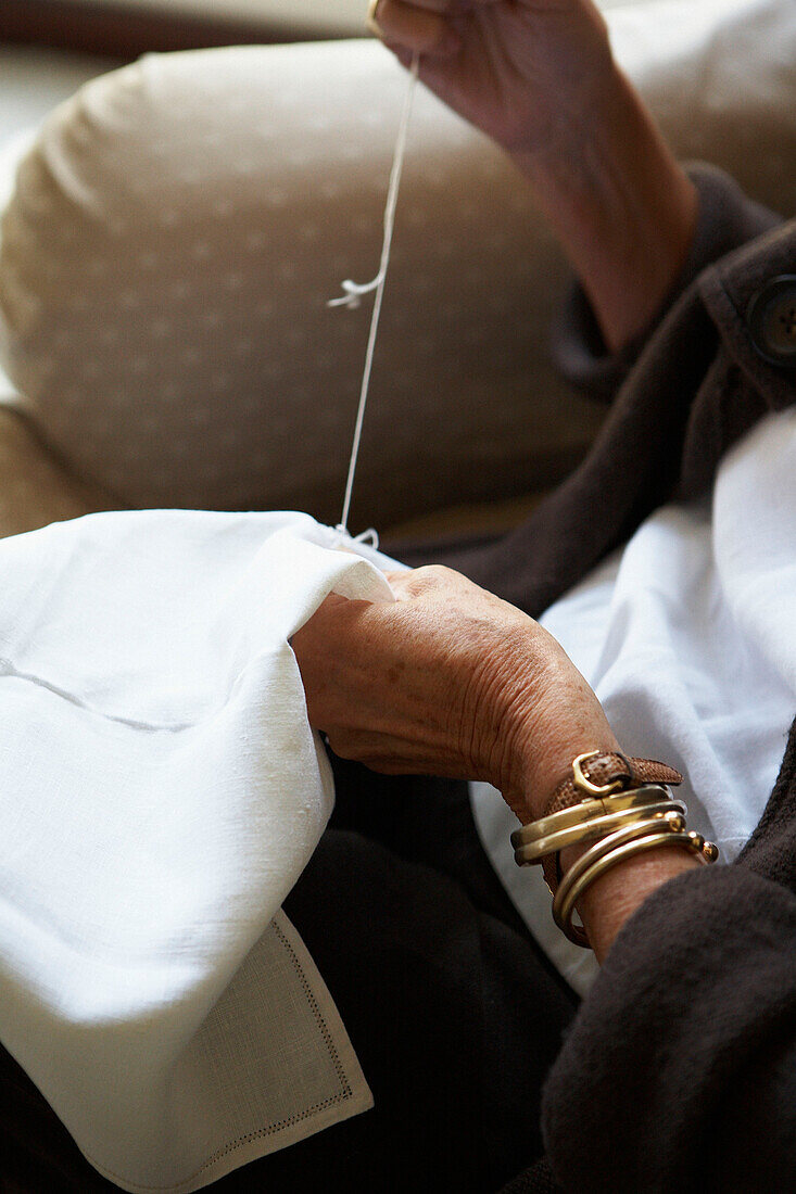 Woman sewing linen cloth with embroidery thread