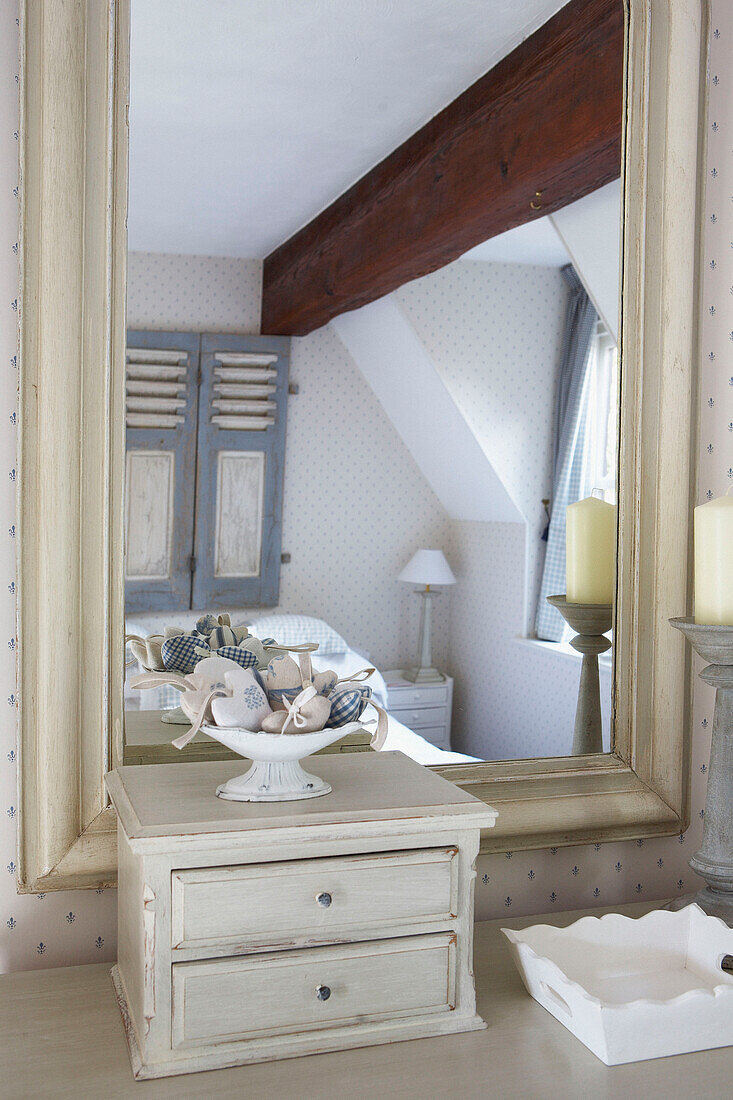 Schlafzimmer mit Balken, reflektiert in einem bemalten Spiegel