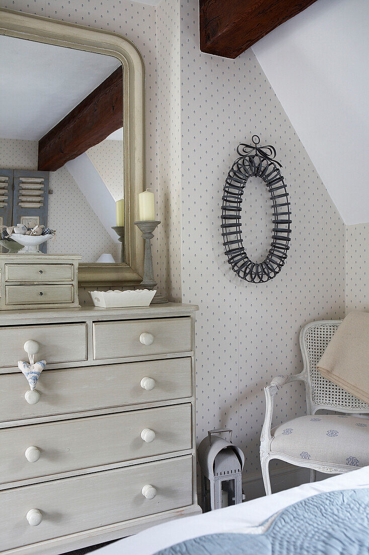 Mirror on painted chest of drawers reflecting beamed bedroom