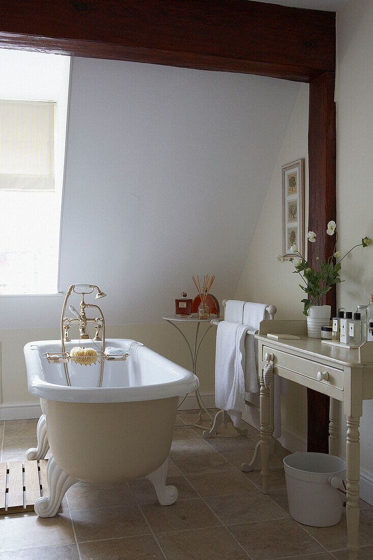 Freestanding clawfoot bath in tiled bathroom with dormer window