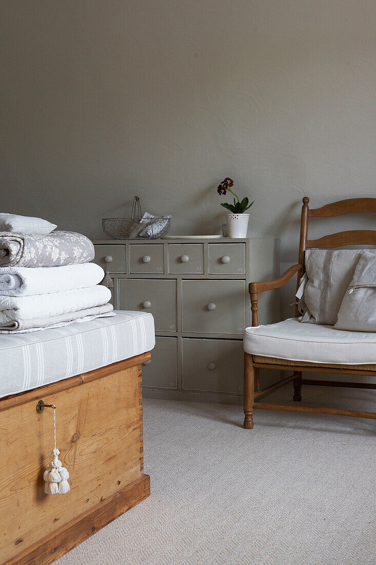 Gefaltete Bettbezüge auf einem Bettkasten mit grau gestrichenem Aufbewahrungsmöbel