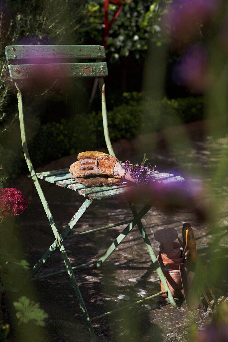 Gartenhandschuhe auf einem Metallklappstuhl im Hintergarten
