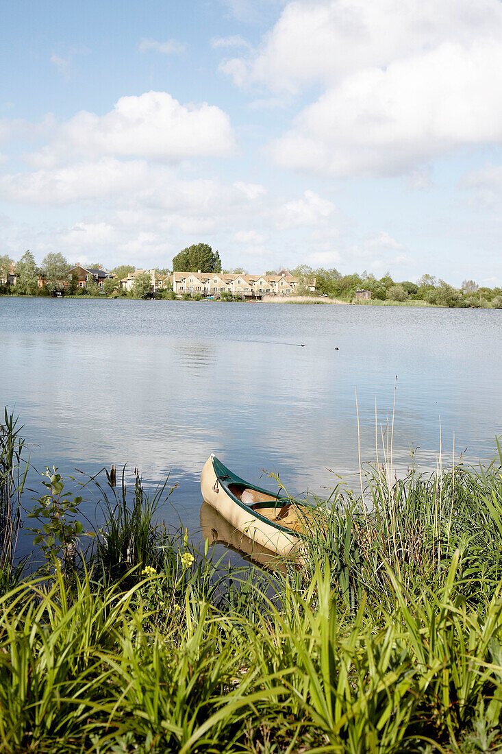 Canoe moored on lake at sustainable housing in conservation estate Gloucestershire