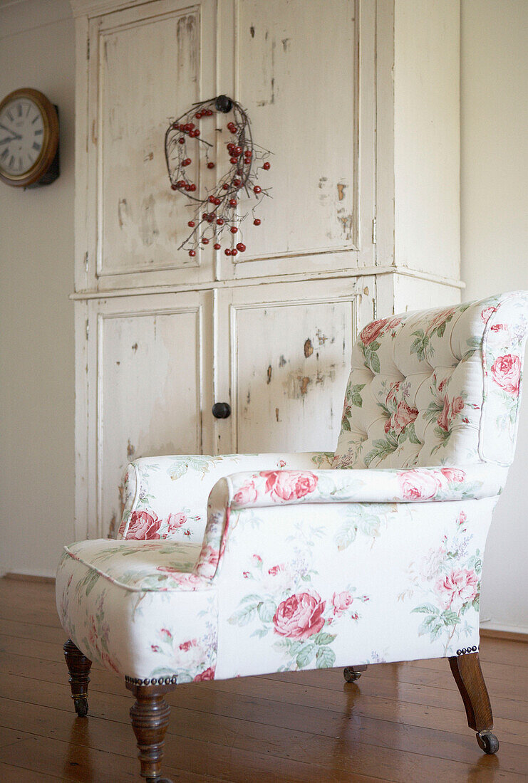 Floral patterned armchair with salvaged cupboard in country house