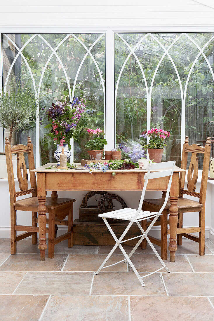 Holztisch und Stühle in einem verglasten Wintergartenanbau