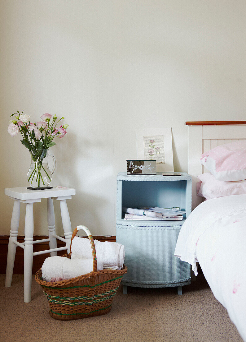Bedside cabinet and cut flowers on painted stool in Wairarapa home North Island New Zealand