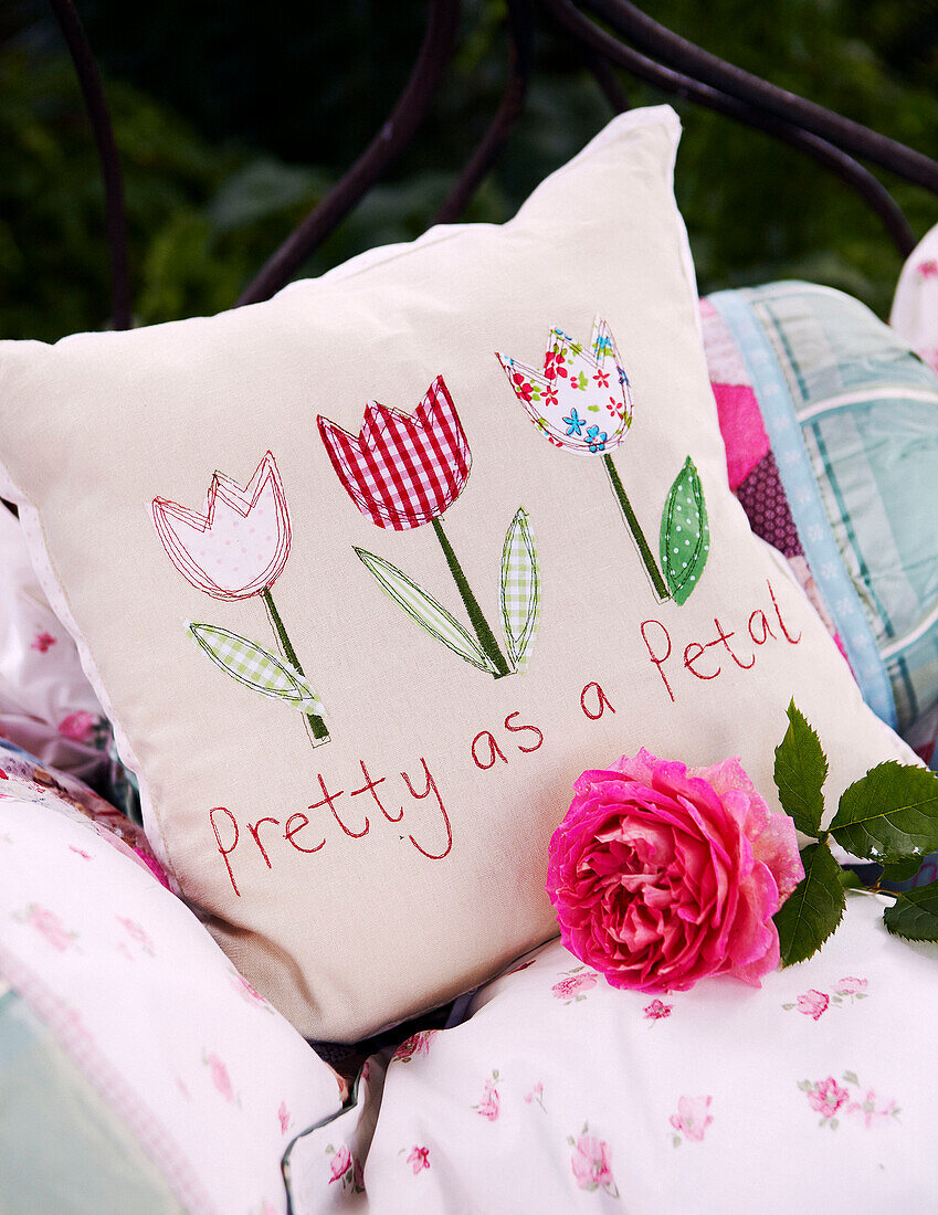 Personalised cushions with single stem rose in garden