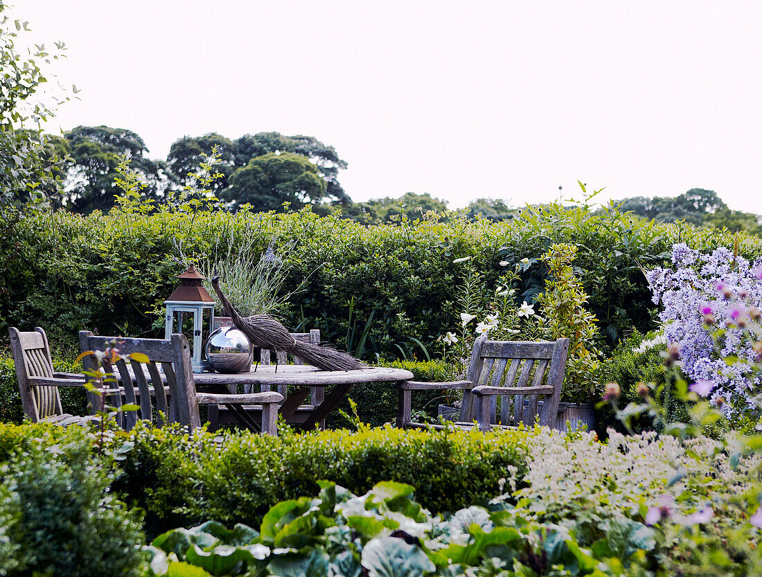 Wooden table and chairs next to hedge in Yorkshire garden