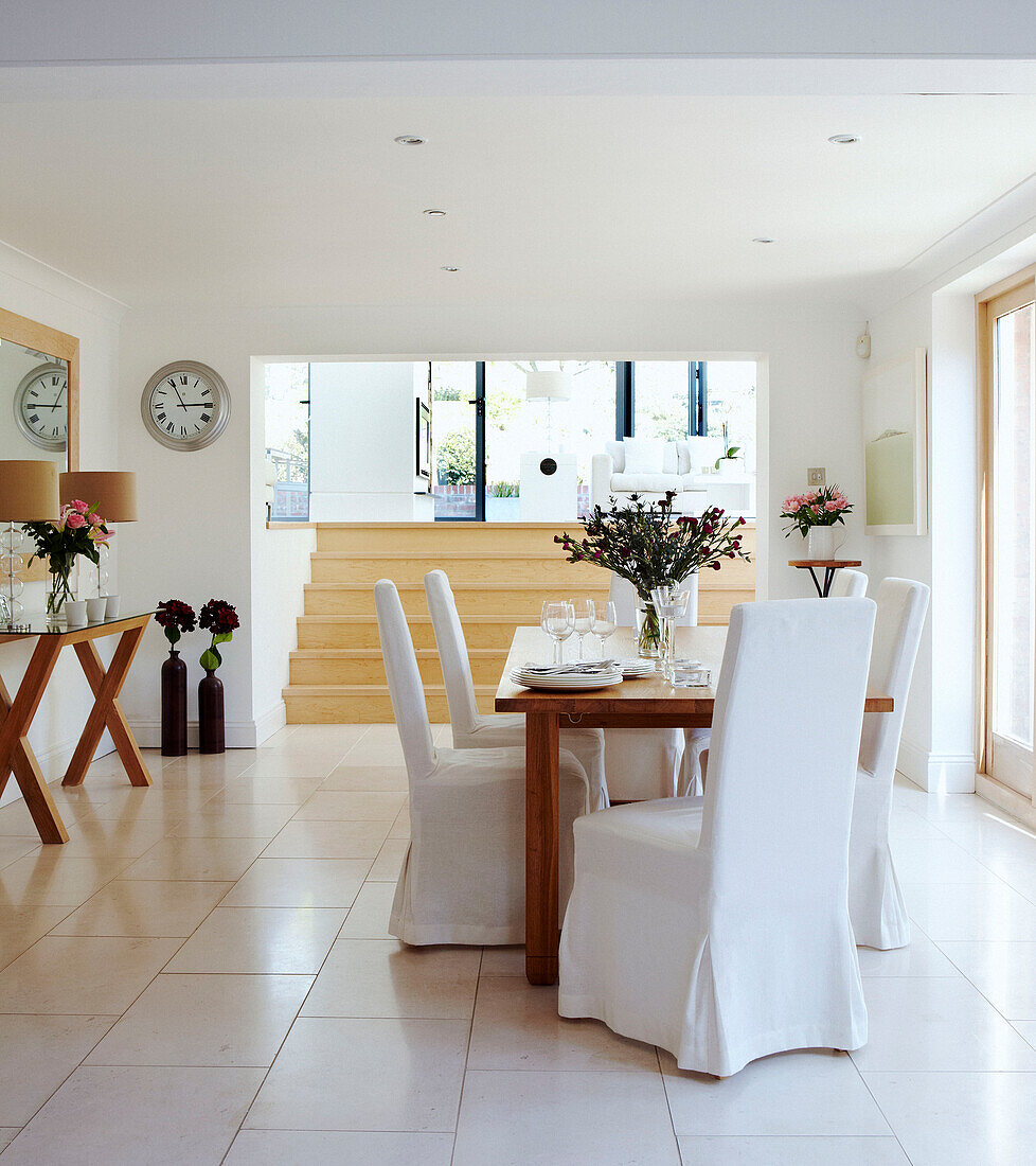 Open plan dining room with white slip covered chairs
