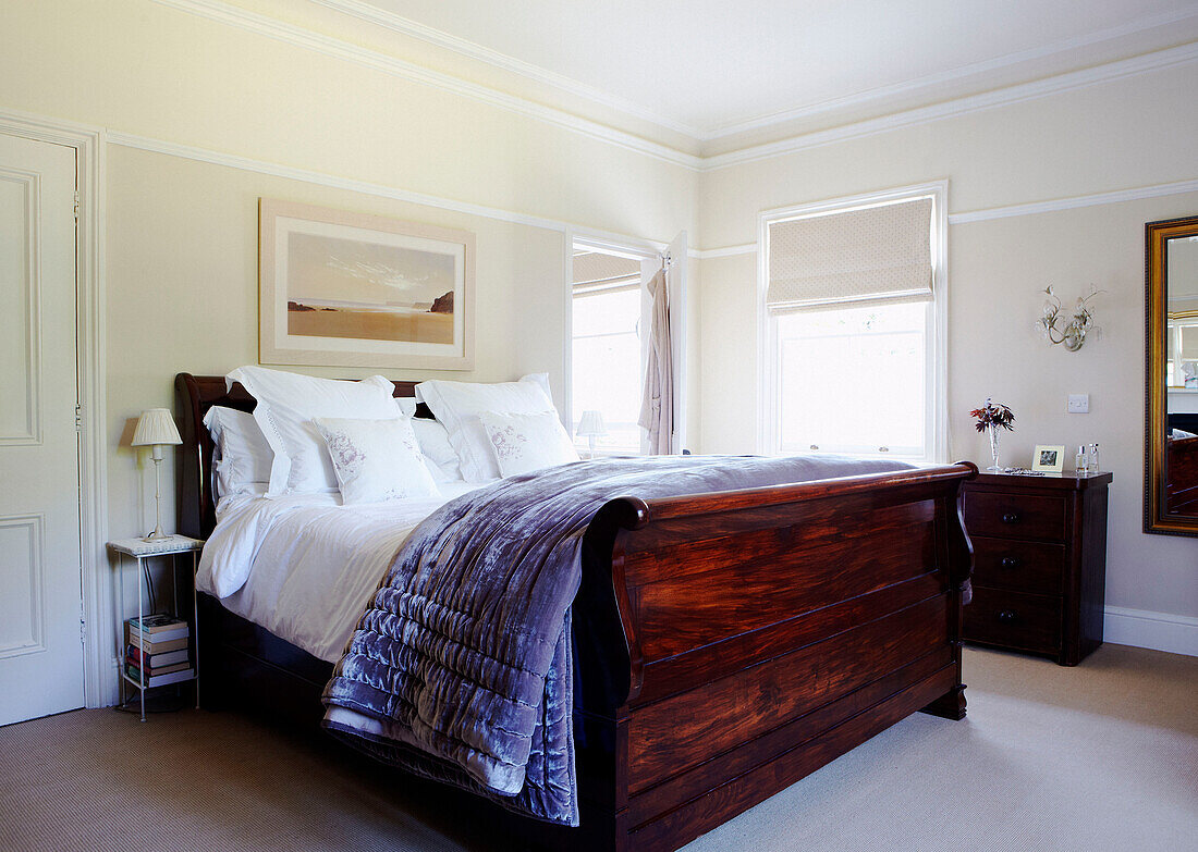 Polished wooden double bed with white bed linen