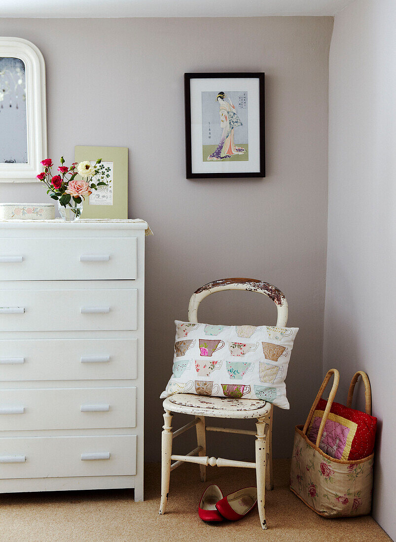 Painted chest of drawers and cushion on salvaged chair in Devon cottage bedroom