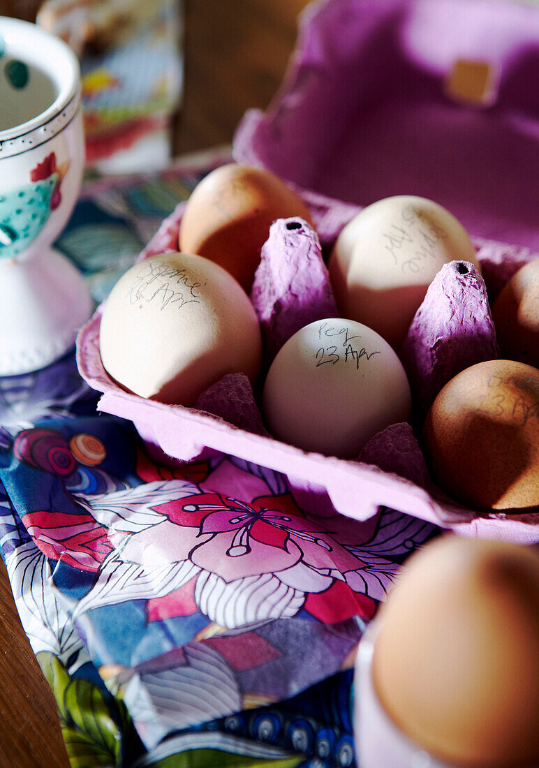 Eier in einem rosa Eierkarton mit handgeschriebenen Daten