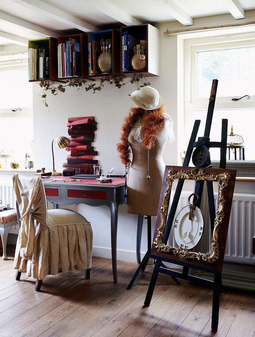 Desk and easel with mannequin at window of country cottage