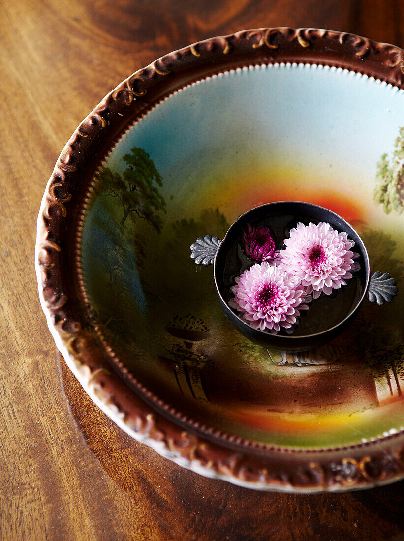 Cut flowers floating in painted ceramic bowl