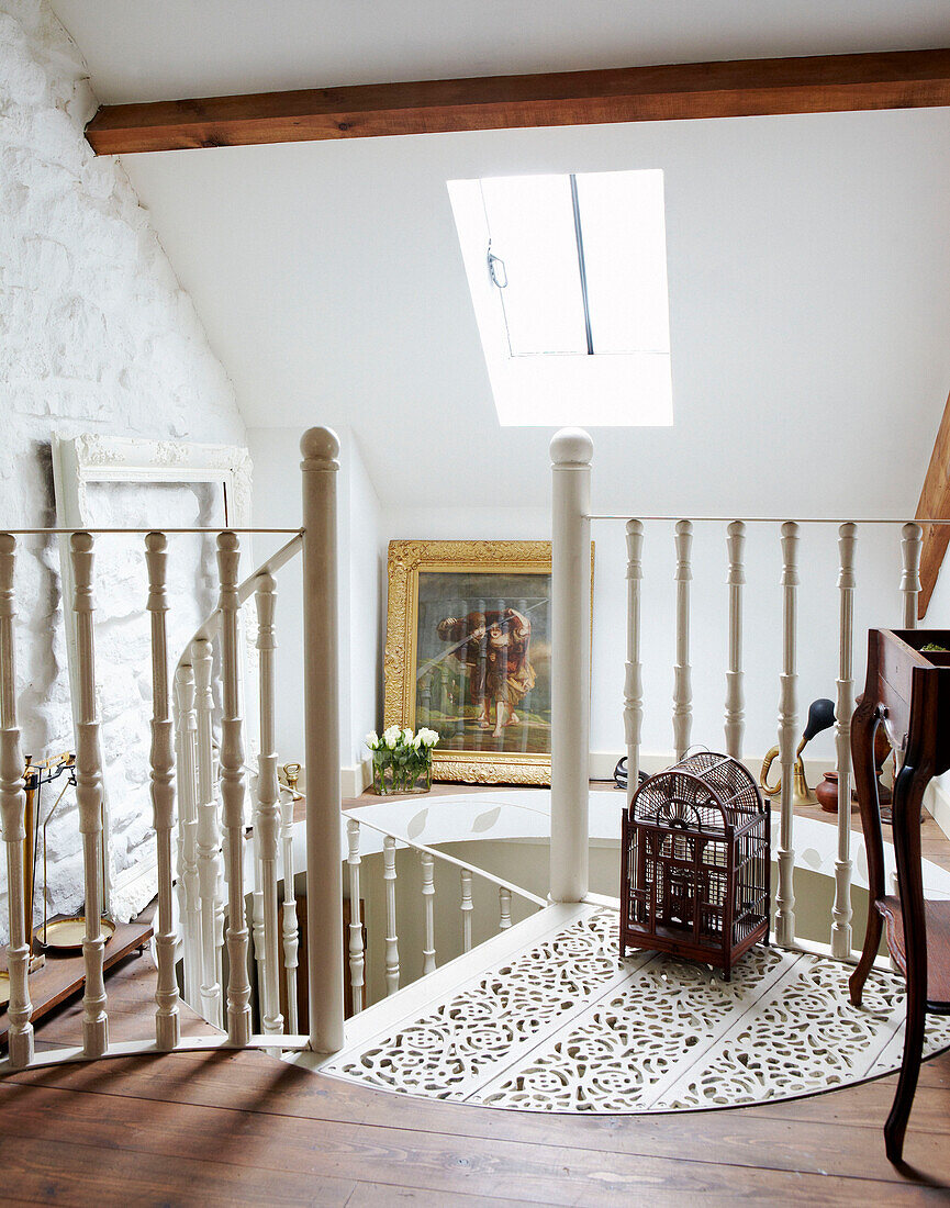 Antiker Vogelkäfig auf dem Treppenabsatz einer Wendeltreppe in einem Landhaus