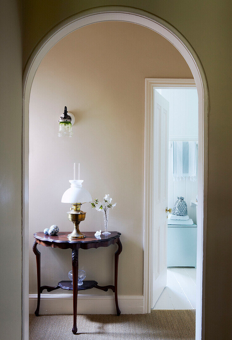 View through arched doorway to demi-lune console table in hallway
