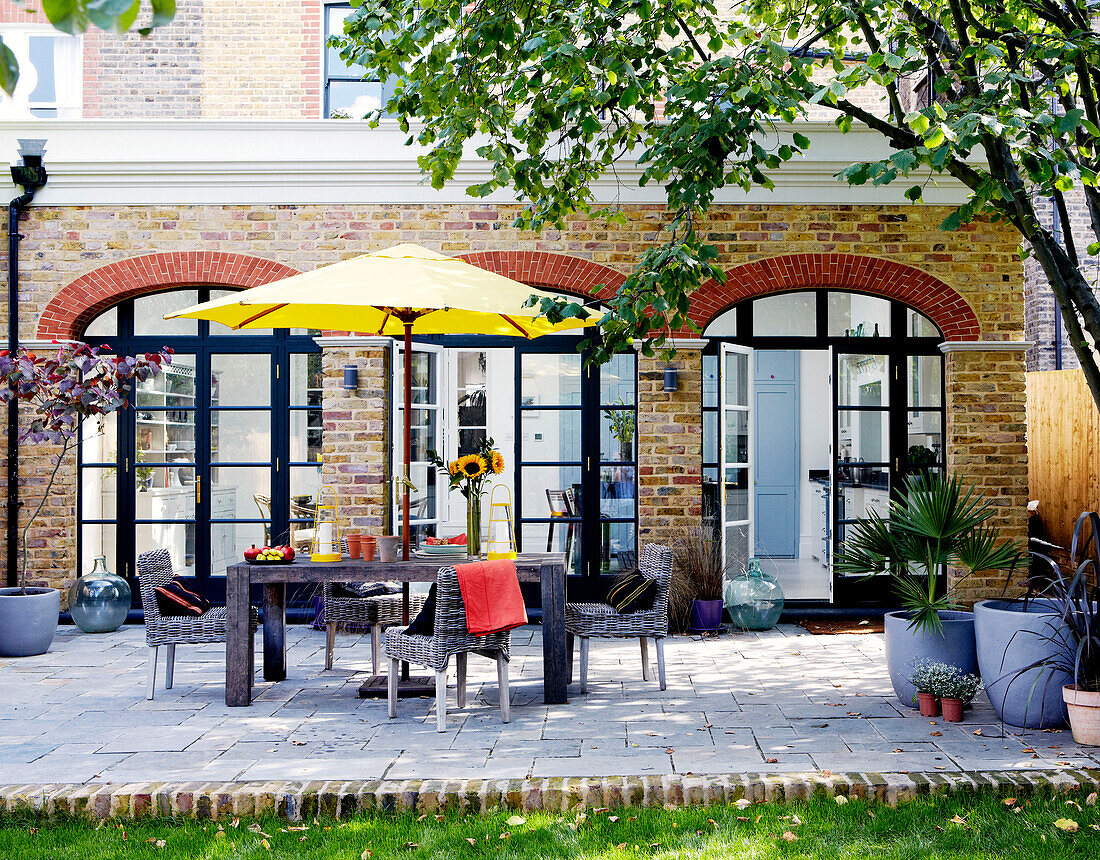 Gemauerte Außenfassade eines Londoner Hauses mit Sonnenschirm auf einer gepflasterten Veranda
