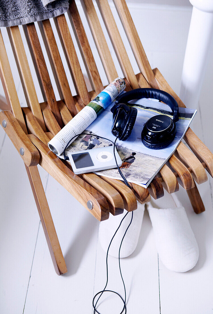 MP3-Player und Kopfhörer mit einer Zeitschrift auf einem Holzstuhl im Londoner Badezimmer