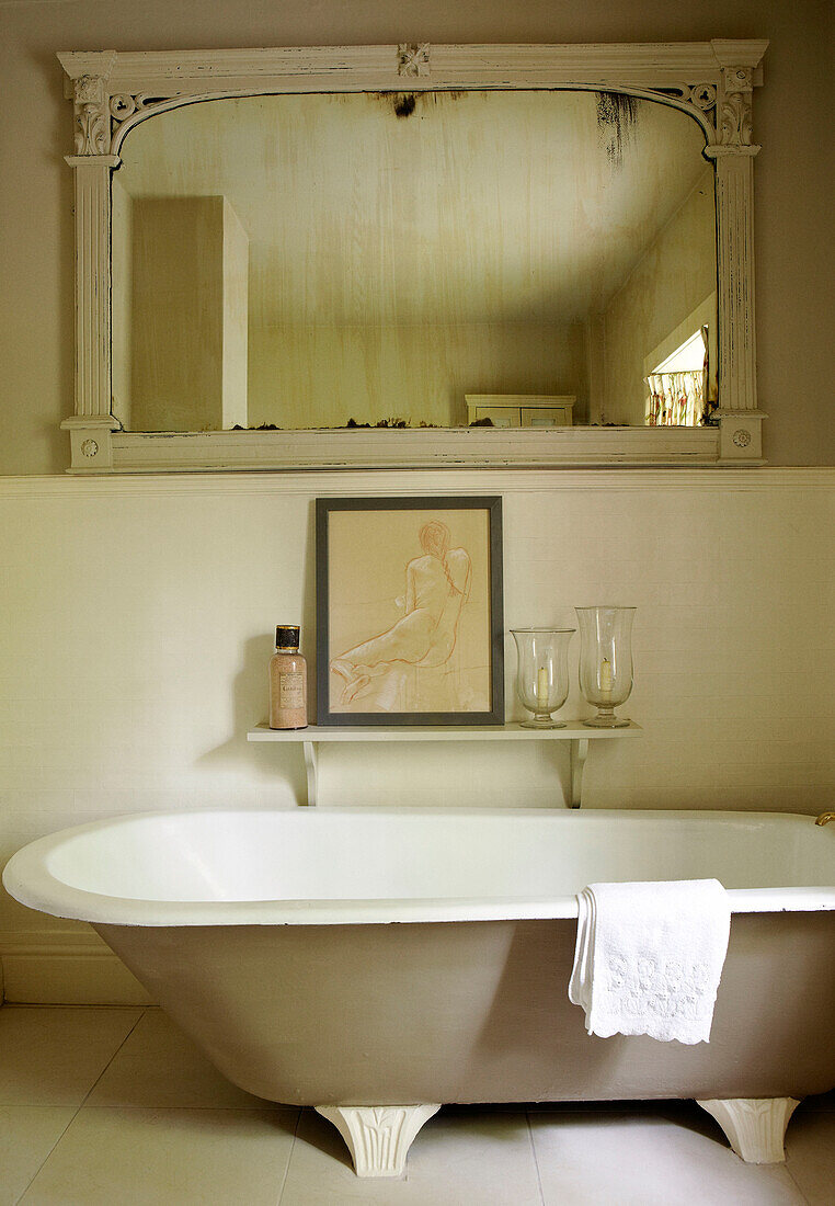 Freistehende Badewanne mit geborgenem Spiegel auf einem Regal und Kunstwerken