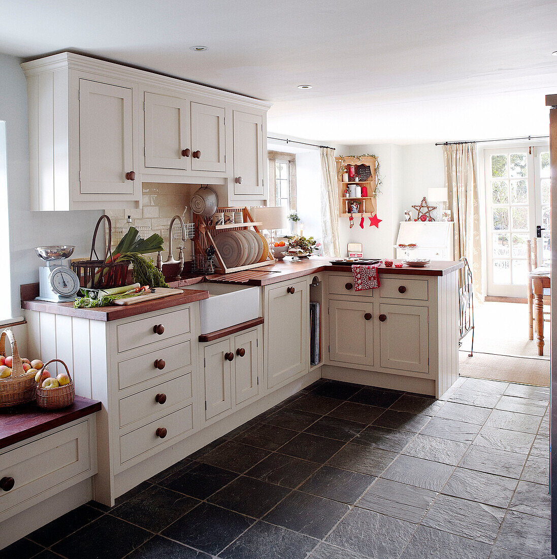 White fitted sunlit kitchen with grey tiled floor