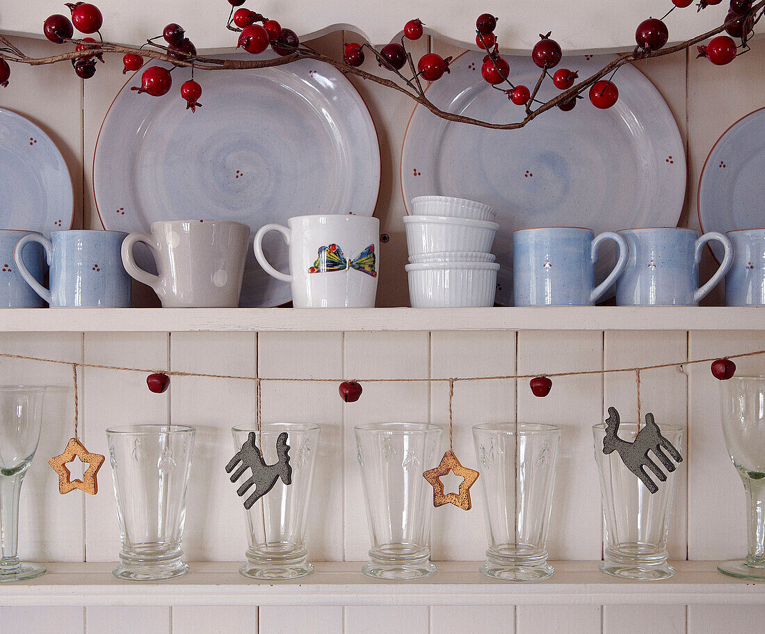 Geschirr und Gläser auf einer Küchenkommode mit Weihnachtsgirlande