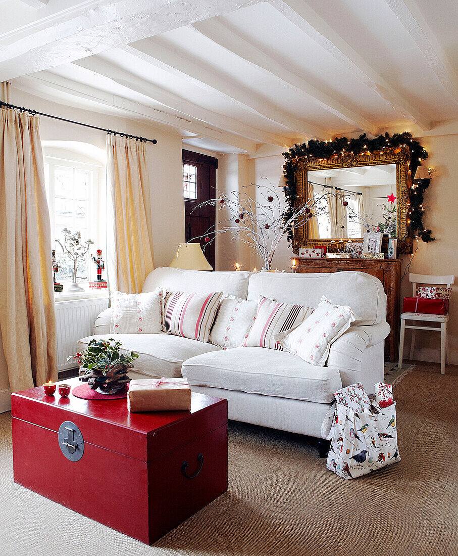 Weißes Zweisitzer-Sofa und rote Truhe im Empfangsraum mit Lichterketten und Girlande über vergoldetem Spiegel