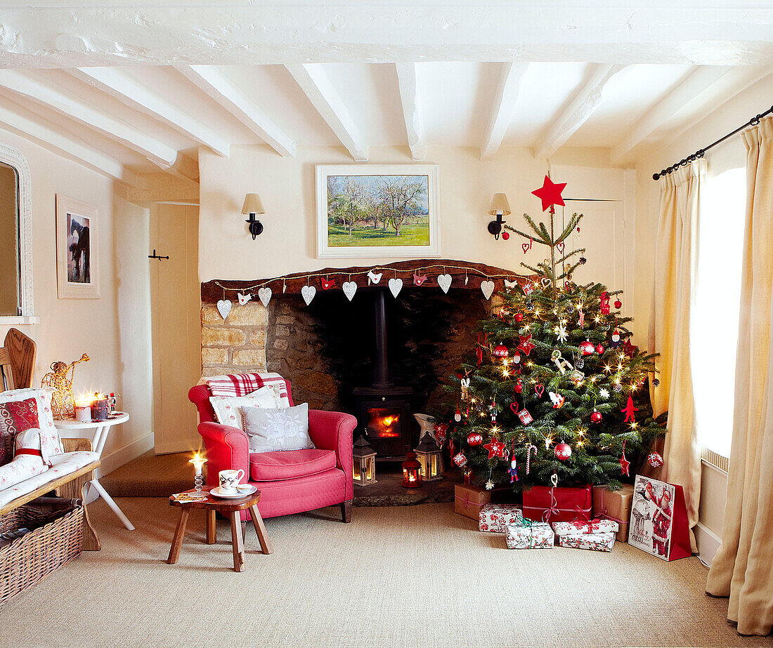 Weihnachtsbaum und roter Sessel am offenen Kamin mit herzförmigen Dekorationen
