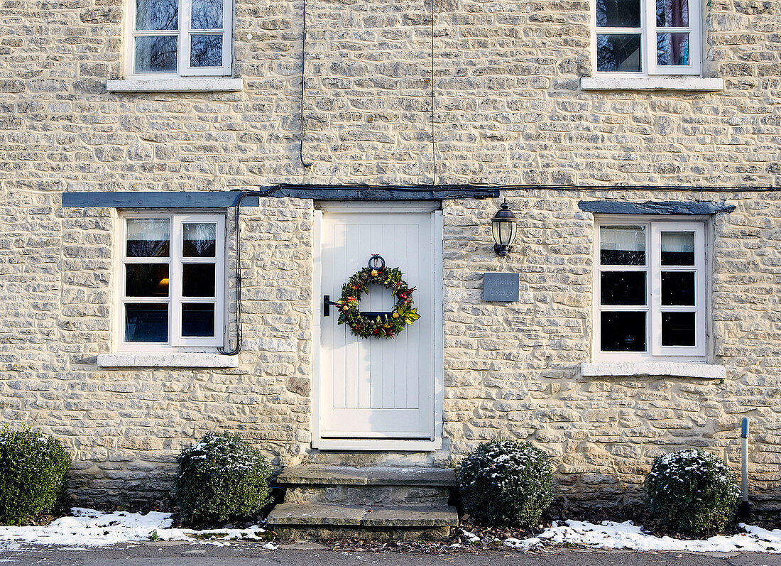 White front door with Christmas garland on stone exterior of country house
