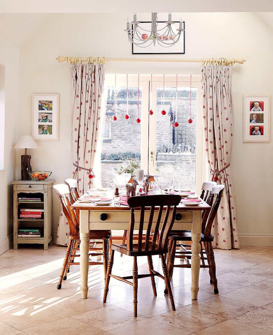 Wooden chairs at table in dining room with Christmas baubles in doorway
