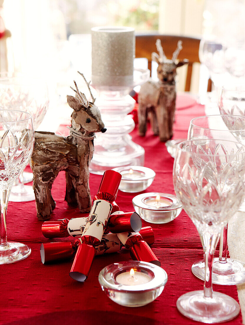 Kristallene Weingläser und Rentierfiguren auf einem weihnachtlichen Esstisch