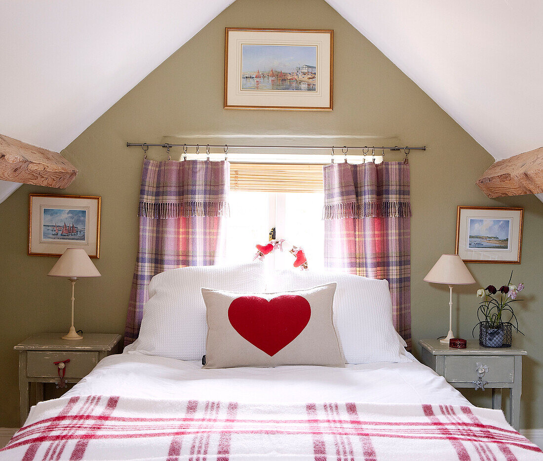 Checked blanket and heart shaped print on cushion on attic bed