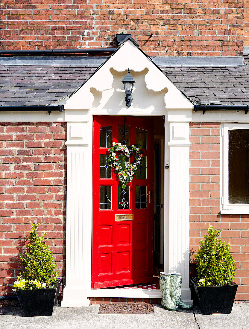 Red front door of brick porch exterior of country home
