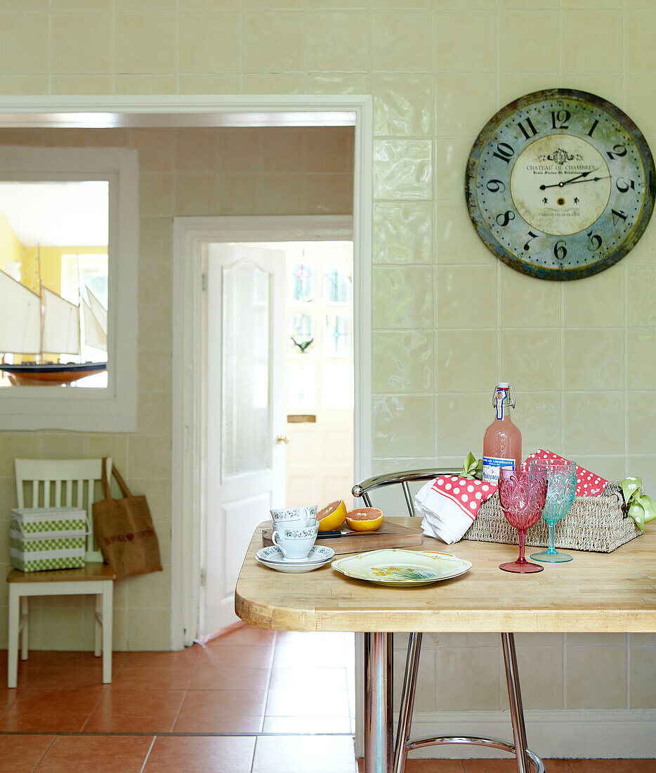 Clock above table with grapefruit drinks in sunlit family kitchen
