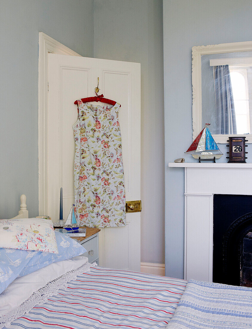 Sommerkleid hängt an der Rückseite der Tür in einem frischen blauen Schlafzimmer