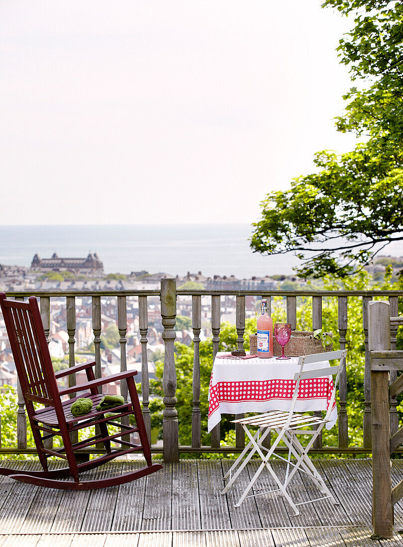 Schaukelstuhl mit Tisch auf einem Balkon im Freien mit Blick auf das Meer