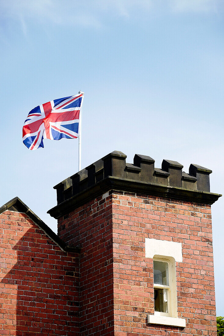 Union Jack weht von der Außenseite eines Backsteinturms