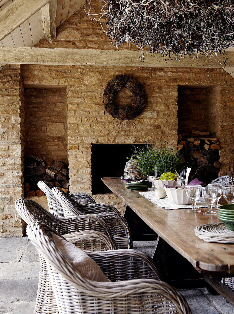 Wicker chairs at table in outdoor room of stone country farm house