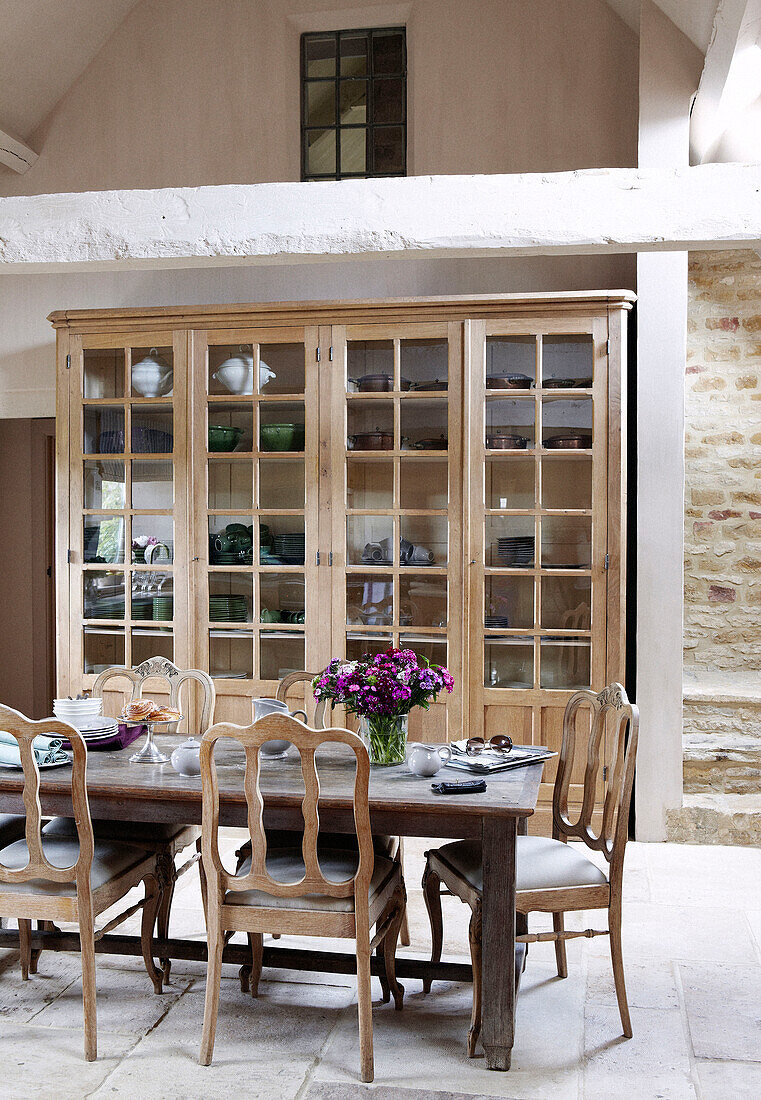 Glasfront-Küchenkommode mit Tisch und Stühlen in einem Landhaus