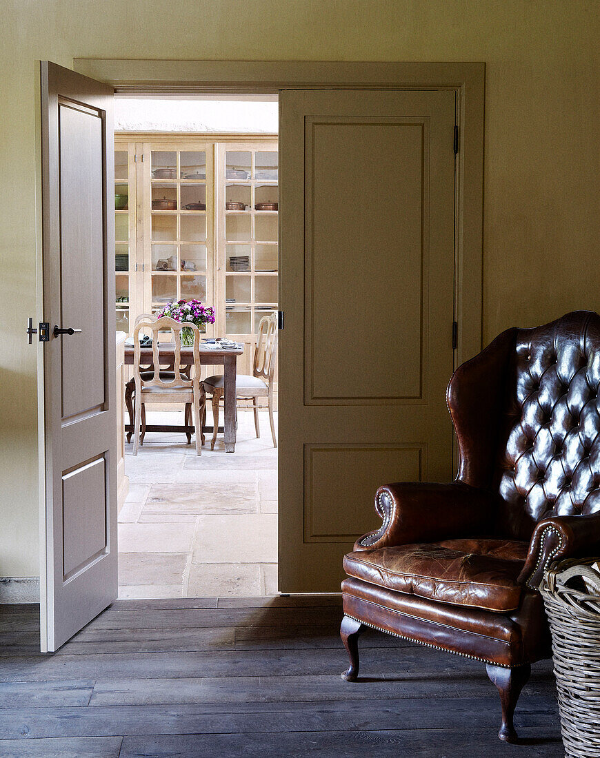 Ledersessel und Blick durch die Tür zur Küche eines Landhauses