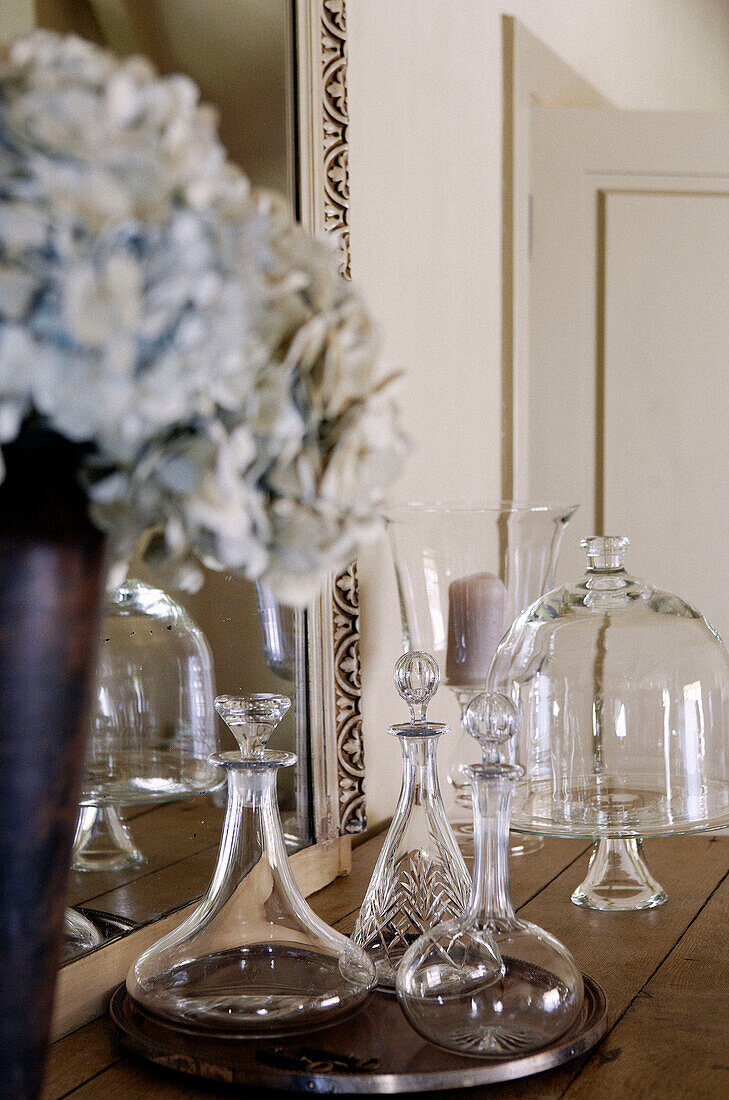 Glaswaren und Schnittblumen auf einer Anrichte in einem Landhaus