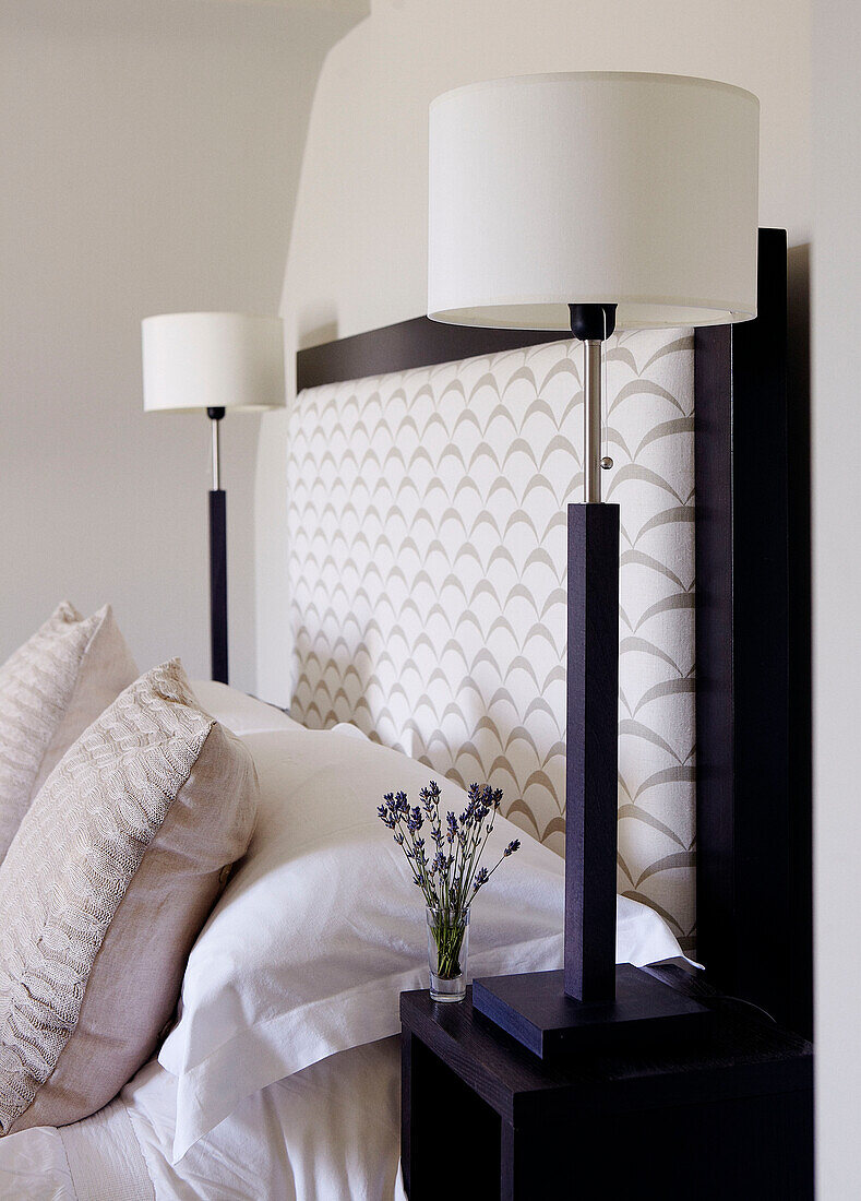White bedside lamps and upholstered headboard with cut lavender