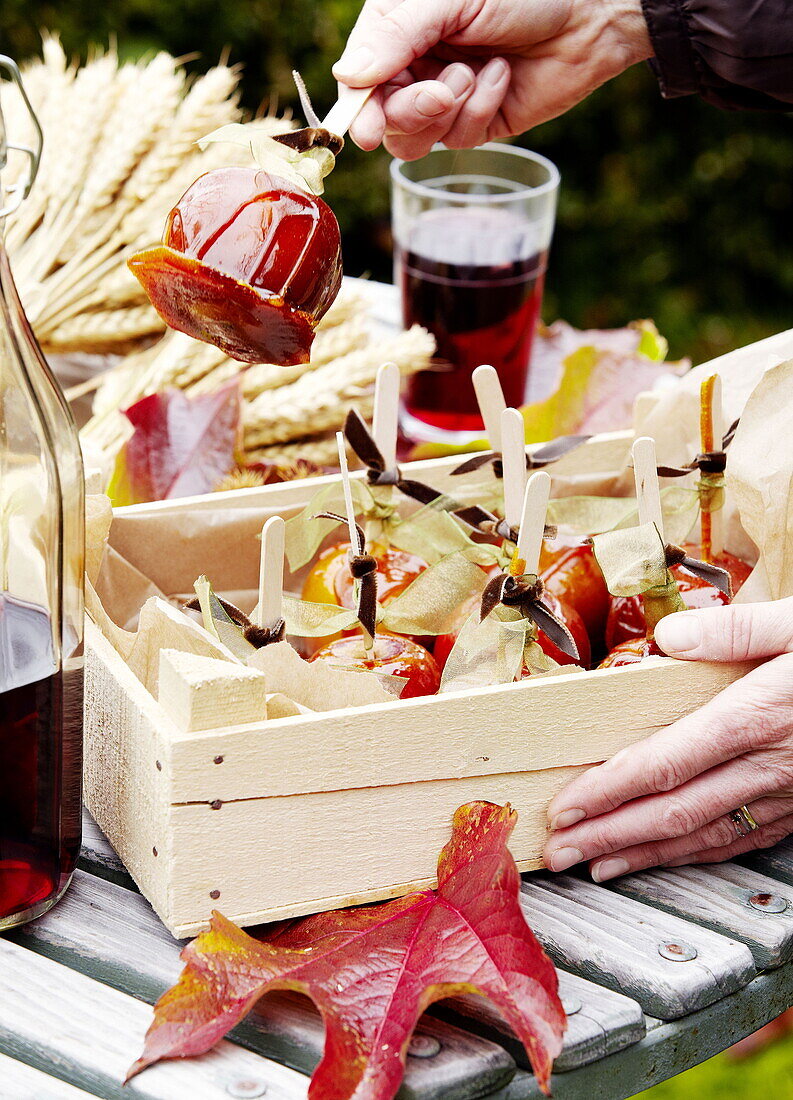 Frau bereitet eine Kiste mit Toffee-Äpfeln im Garten von Essex, England, vor