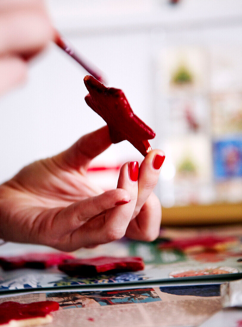 Frau malt roten Weihnachtsschmuck in Sternform
