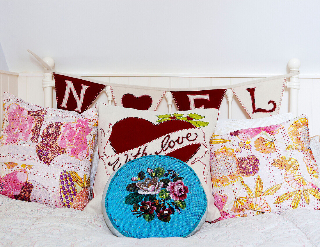 Embroidered cushions with bunting for Noel on metal bed