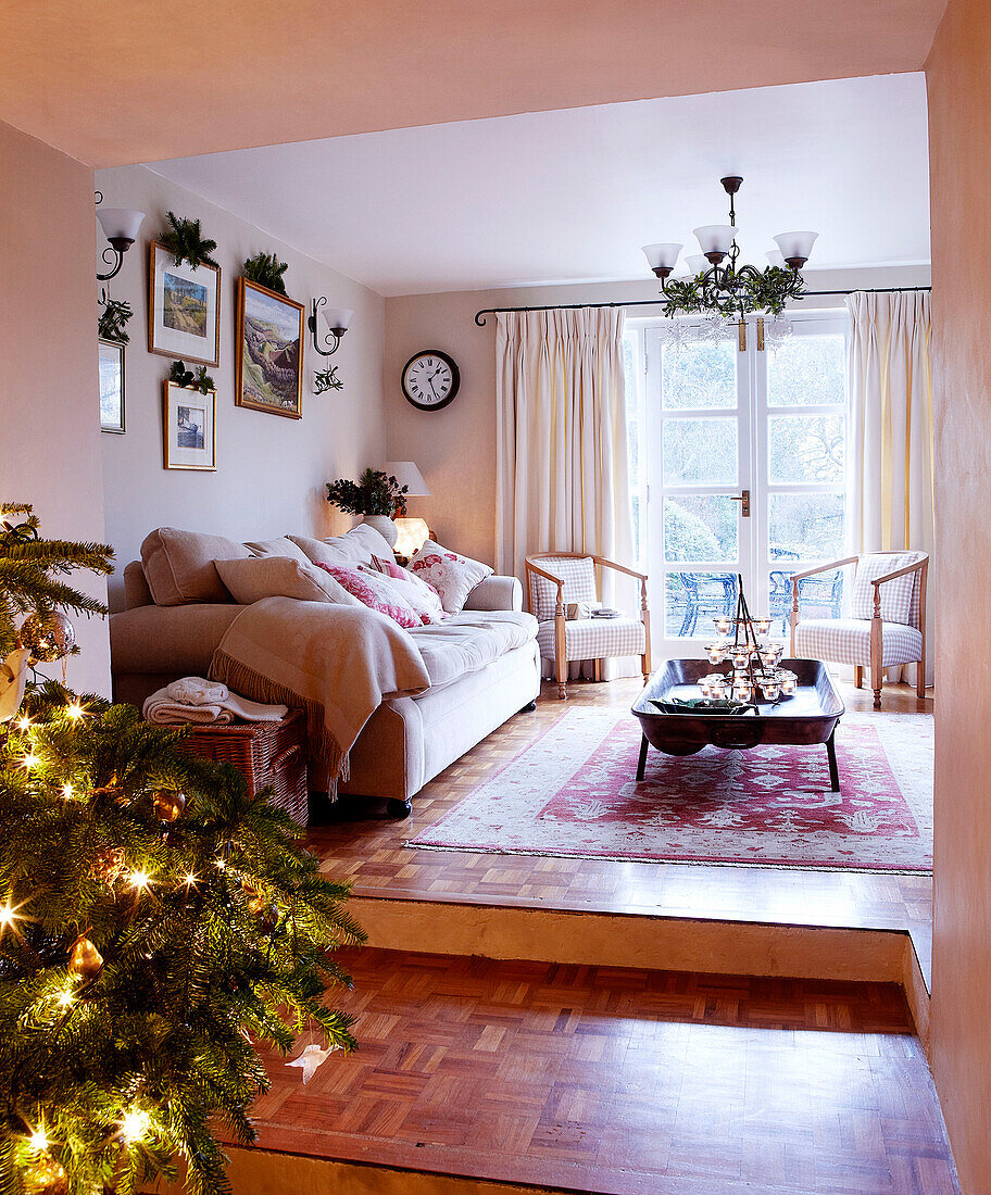 Weihnachtsbaum mit Lichterketten in einem Split-Level-Wohnzimmer mit cremefarbenem Sofa
