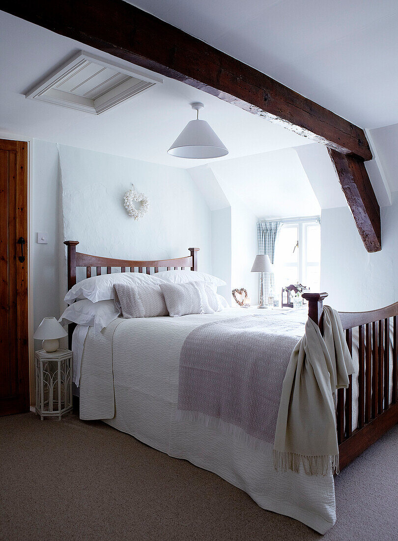 Schlafzimmer mit Holzbalken und pastellrosa Decken