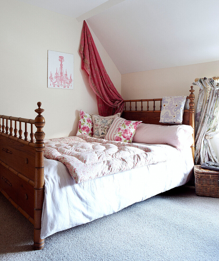 Rosa Sari-Stoff über dem Bett mit Steppdecke und Blumenkissen
