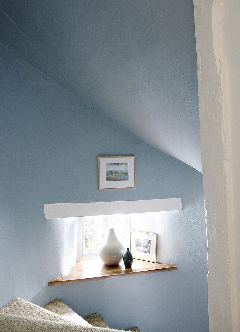 Small staircase window in light blue attic renovated Cotswolds mill house England UK
