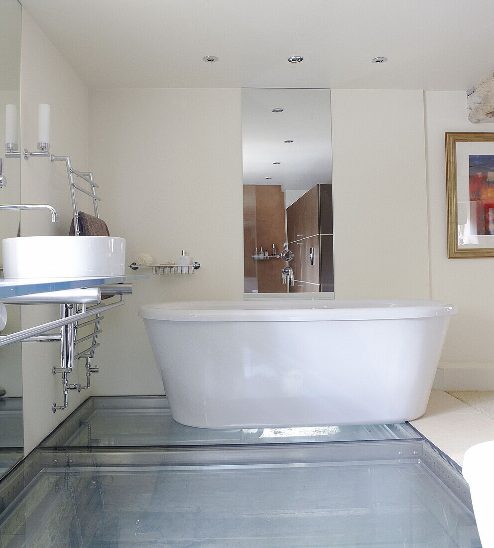 Freestanding bath with glass floor in renovated Cotswolds mill house England UK