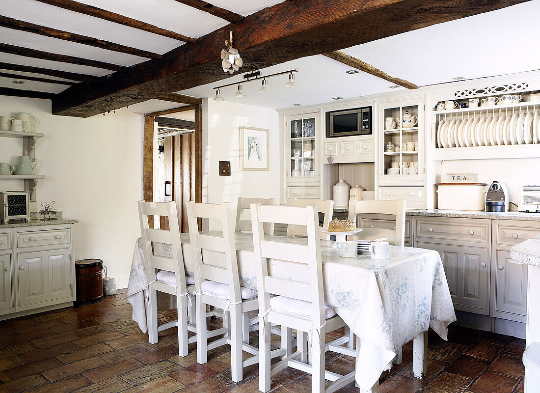 Tisch und Stühle mit Einbauschrank in der Balkenküche eines umgebauten Bauernhauses in Forest Row Surrey England UK